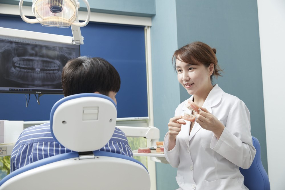치과교정과 전문의 김선 원장이 치아 모형을 들고 환자에게 투명교정 원리를 설명하는 모습