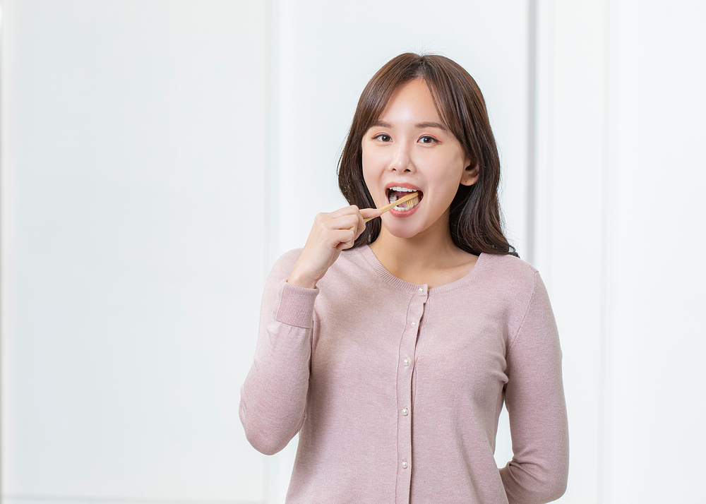 정면을 바라보며 칫솔질을 하는 중년 여성